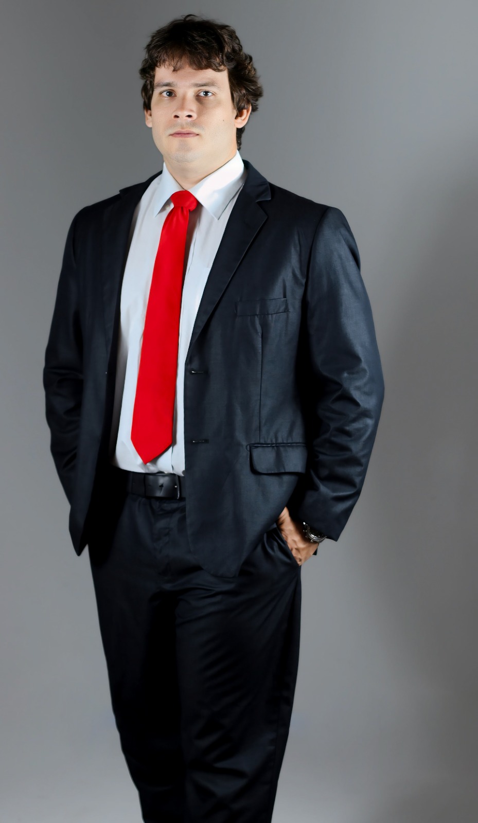 Dr. Alexandre Moreira Puchetti em foto de corpo inteiro, com postura profissional e gravata vermelha.